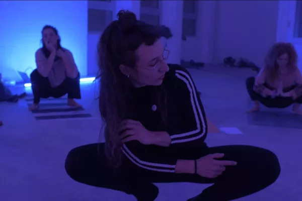professeure de cours de yoga bruxelles qui montre une posture de yoga dans une pièce bleue