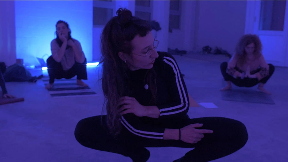 professeure de cours de yoga bruxelles qui montre une posture de yoga dans une pièce bleue