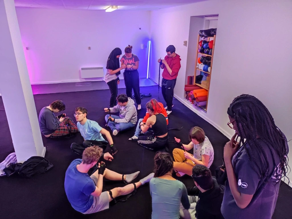 groupe de jeunes en situation de handicaps légers qui mettent leurs bandages de boxe